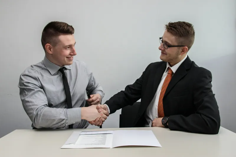 Stretta di mano tra consulente e cliente sopra un documento